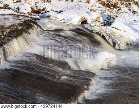 A Stream Of Water Flows Among Ice And Snow. Dark Cascade Stream Of Water Among White Snow And Ice