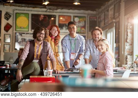 Group of young creative people in a pleasant atmosphere in the office is posing for a photo while working together