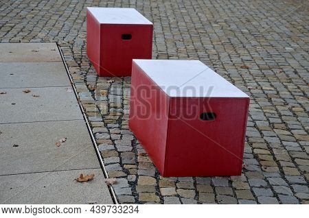 Red Plastic Benches In The Shape Of Blocks With Handles. The Square Is Paved With Granite Cubes. San