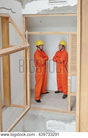 Positive Contractors Standing Inside Building Under Construction And Discussing Rennovation Process