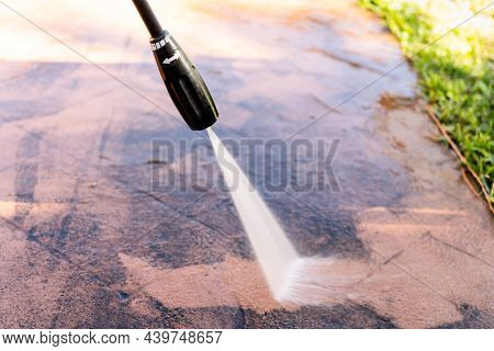 Cleaning Dirty Backyard Paving Tiles With Pressure Washer Cleaner.
