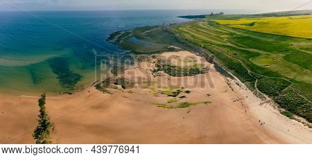 Embleton Bay and Burn with sandy beach with the ruins of Dunstanburgh Castle