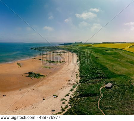 Embleton Bay and Burn with sandy beach with the ruins of Dunstanburgh Castle