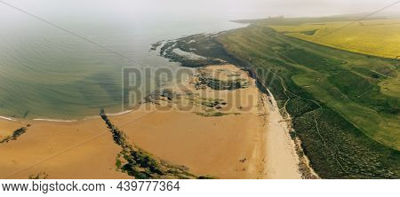 Embleton Bay and Burn with sandy beach with the ruins of Dunstanburgh Castle