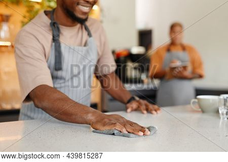 Unrecognizable Young African American Cafe Worker Wiping Off Dust From Kitchen Counter In Morning Wi