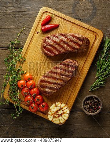 Juicy And Tender Two Ketogenic Top Blade Beefsteaks On Wooden Board With Herbs And