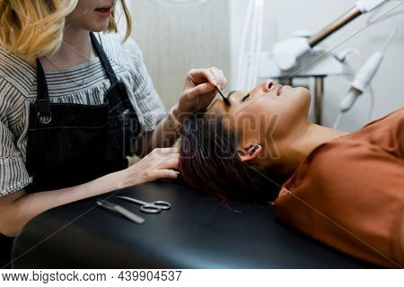 Beautician giving eyebrow treatment to a customer at a beauty salon