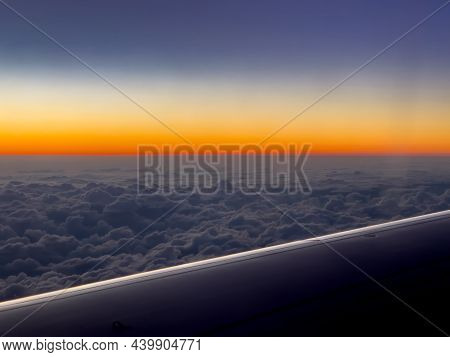 View From The Plane On Part Of Its Wing, Flying Over A Thick Layer Of Clouds In The Evening Sky. The