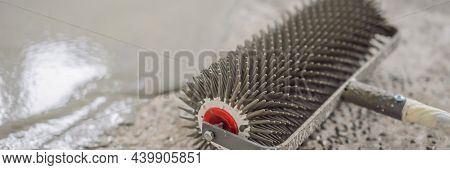 Plasterer During Floor Covering Works With Self-levelling Cement Mortar, Uses A Needle Roller Banner