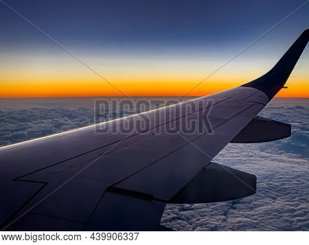 View From The Plane On Part Of Its Wing, Flying Over A Thick Layer Of Clouds In The Evening Sky. The