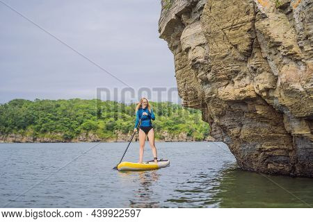 Young Women Having Fun Stand Up Paddling In The Sea. Sup. Red Hair Girl Training On Paddle Board Nea