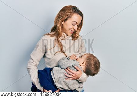 Young caucasian woman holding and hugging her son breastfeeding him, maternity lactation