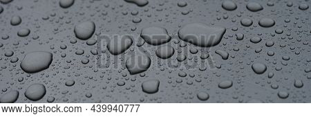Closeup Of Raindrops On Black Hood Of Car Background. Rainy Day Weather Forecast Concept