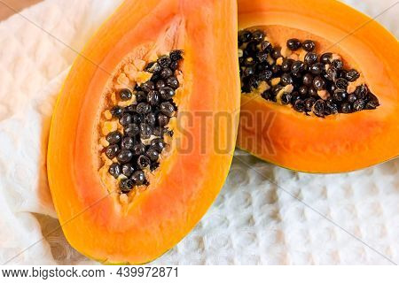 Bright Orange Exotic Papaya Fruit Halved Slices With Black Seeds On Light Background.