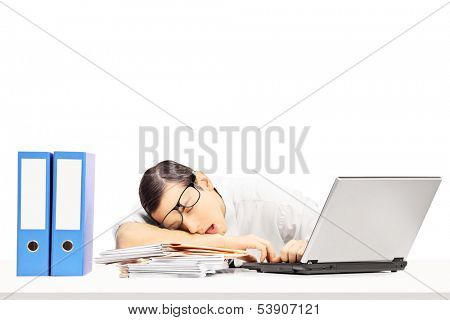 Exhausted young businessman sleeping on a desk at his workplace, isolated on white background