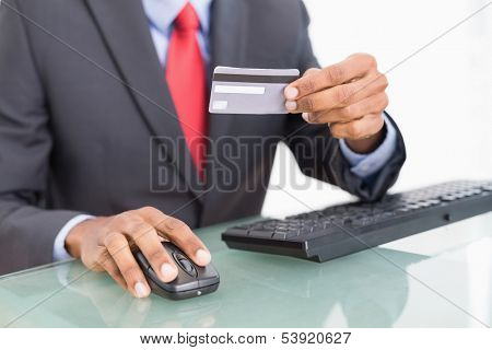 Close up mid section of a businessman doing online shopping through computer and credit card