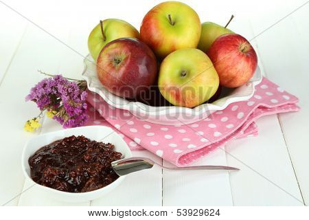 Juicy apples on plate on white wooden table
