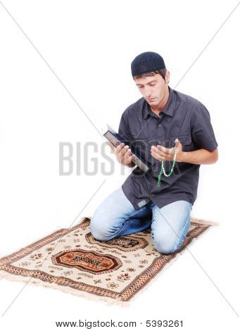 muslimischen Mann hält Holly Buch Qoran und beten auf traditionelle Weise