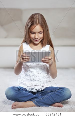 Child playing on tablet pc sitting on a carpet at home