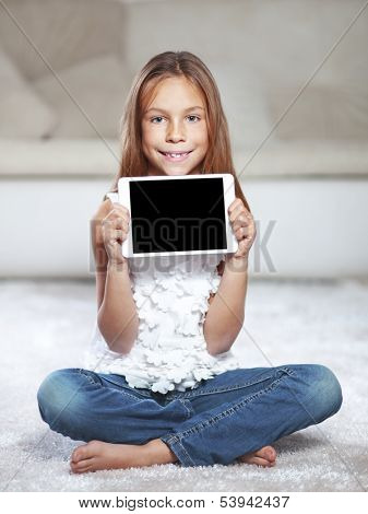 Child playing on tablet pc sitting on a carpet at home