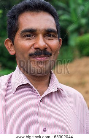 ELLA, SRI LANKA - MARCH 2, 2014: Portrait of local farmer posing on tea plantation. Ella is famous for the tea plantations and stunning views across the countryside.