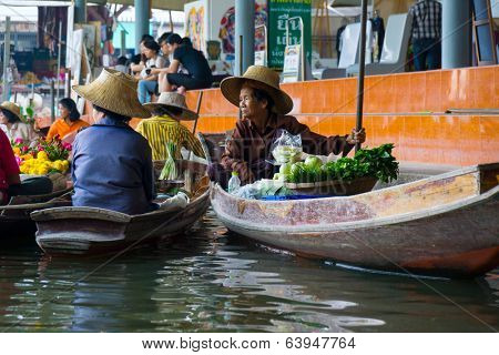 RATCHABURI, THAILAND - MARCH 24: Local peoples sell fruits, food and souvenirs at famous tourist attraction Damnoen Saduak floating market on March 24, 2014 in Ratchaburi, Thailand.