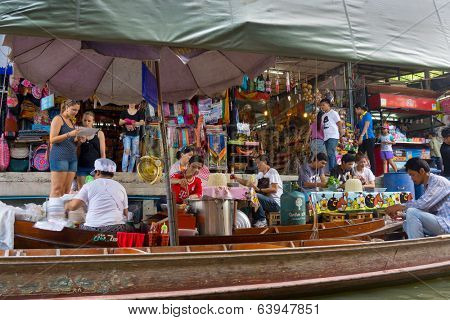 RATCHABURI, THAILAND - MARCH 24: Local peoples sell fruits, food and souvenirs at famous tourist attraction Damnoen Saduak floating market on March 24, 2014 in Ratchaburi, Thailand.