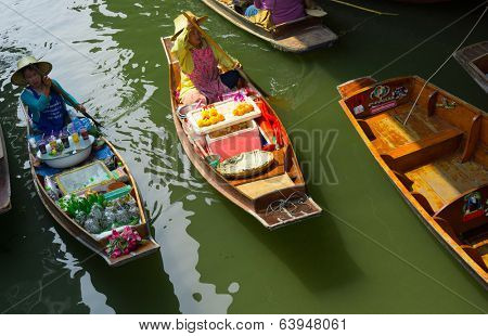 RATCHABURI, THAILAND - MARCH 24: Local peoples sell fruits, food and souvenirs at famous tourist attraction Damnoen Saduak floating market on March 24, 2014 in Ratchaburi, Thailand.