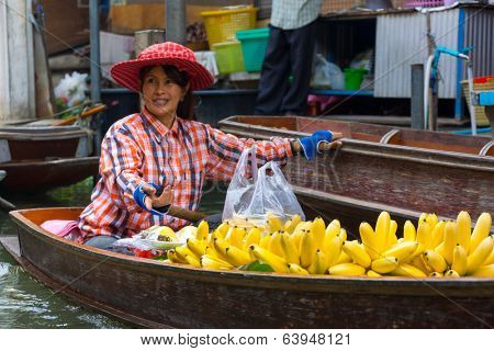 RATCHABURI, THAILAND - MARCH 24: Local peoples sell fruits, food and souvenirs at famous tourist attraction Damnoen Saduak floating market on March 24, 2014 in Ratchaburi, Thailand.