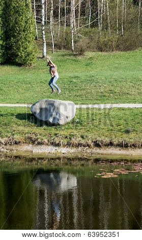 Young Woman Jumping On The Big Stone