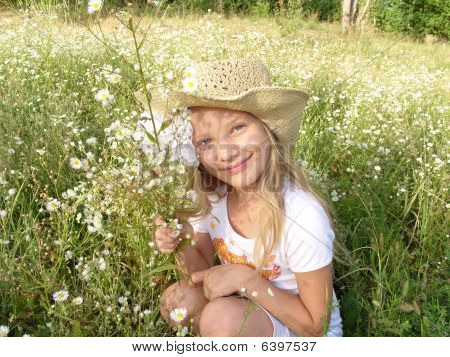 Image de petite fille, assis parmi les fleurs sauvages sur le terrain