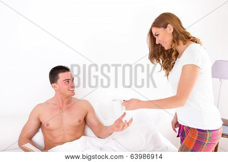 Wife Giving Husband Coffee In Bed