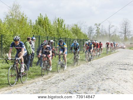 The Peloton On A Dusty Cobblestoned Road