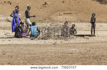 Hamar Men Teach Hunting Young Boys On A Dry River Bed.