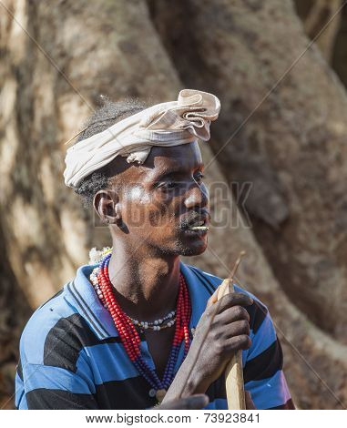 Traditionally Dressed Hamar Man With Chewing Stick In His Mouth At A Bull Jumping Ceremony.