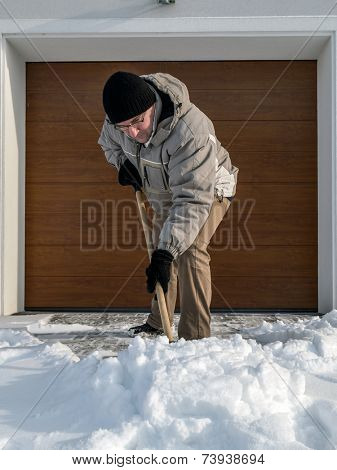 Man clearing driveway of snow with shovel after heavy snowing