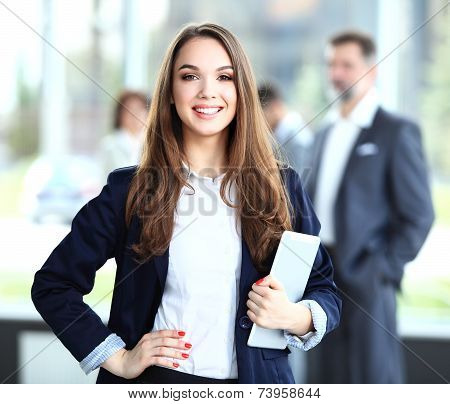 Business woman standing in foreground with a tablet