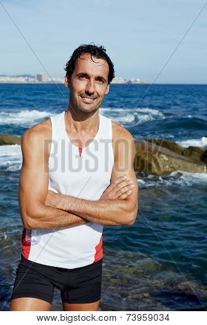 Portrait of smiling runner standing on rocks at sunny day