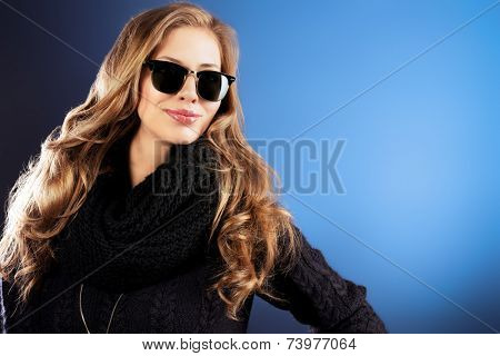 Close-up portrait of a smiling young lady with beautiful hair wearing black sunglasss.