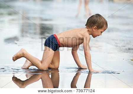 Little Boy Crowls  In Puddle