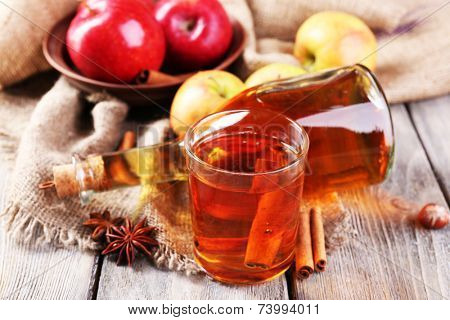Apple cider with cinnamon sticks, spices and fresh apples on wooden background