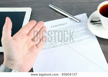 Man Sitting In A Table Showing, Offering  A Contract And Where The Signer Must Sign