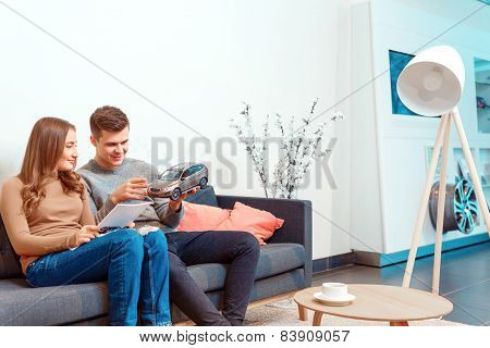 Happy young couple in dealership