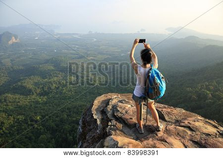 woman hiker use cellphone taking photo at mountain peak cliff