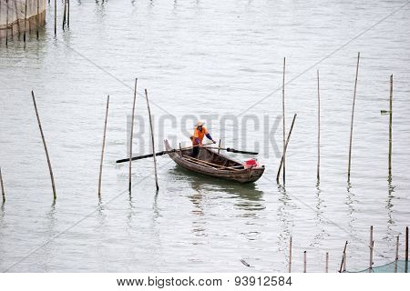 XIAPU, CHINA - JUNE 4, 2015: A farm worker rows out to inspect the nets of a large crab farm in the sea. Aquaculture is an important economy in the eastern coast seaside towns in Xiapu County.