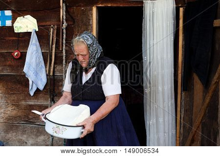 SALCIUA, ROMANIA - SEPTEMBER 14, 2016: Old woman selling cheese at the farm in the mountains
