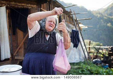 SALCIUA, ROMANIA - SEPTEMBER 14, 2016: Old woman selling cheese at the farm in the mountains