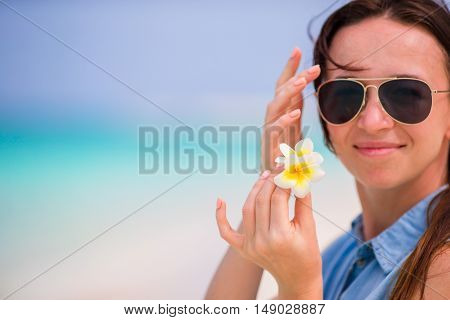 Young beautiful woman during tropical beach vacation. Enjoy suumer vacation alone on the beach at Africa with frangipani flowers in her hair