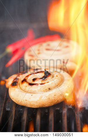 cumberland sausage, spiral pork sausage on bbq grill with flame, homemade