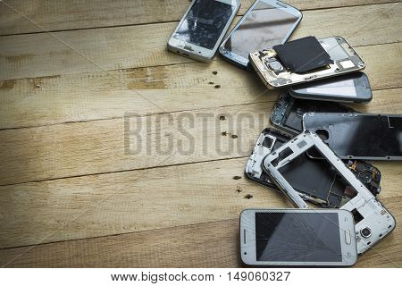 Broken smart phone with space in wooden texture background